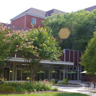 A view of a building on a campus surrounded by trees and greenery.