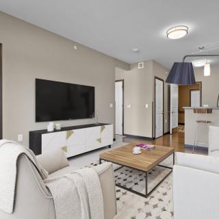 A modern living room with neutral tones, featuring a sofa, coffee table, and wall-mounted TV.