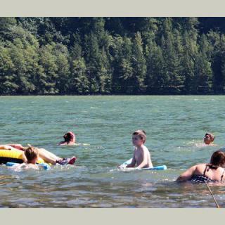 People enjoying a swim in a scenic lake surrounded by lush green trees.