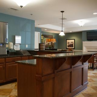 A modern kitchen with a bar counter, featuring wooden cabinetry and pendant lighting.