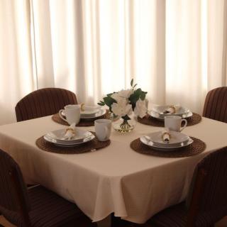 A neatly set dining table with a floral centerpiece and four place settings, illuminated by soft natural light.