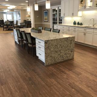 A modern kitchen with a large granite island and wooden flooring.