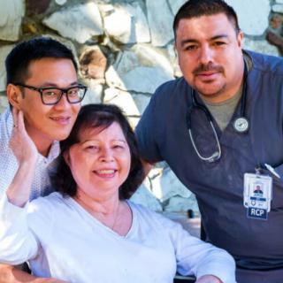A group of healthcare professionals with a patient, all smiling.