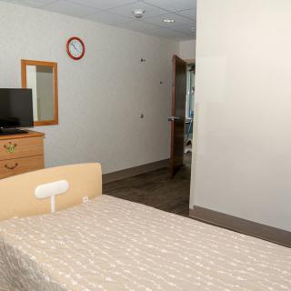 A clean hospital room with a bed, television, and simple furniture.