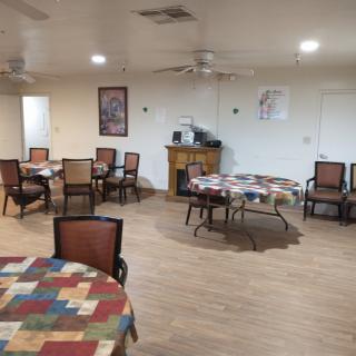 A spacious dining area with several tables and chairs arranged neatly, featuring colorful table covers and wall decorations.