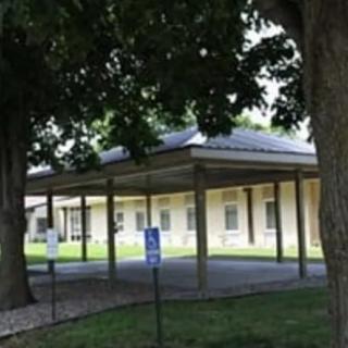 A building surrounded by trees with a covered walkway in front.