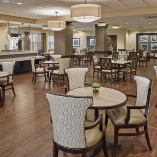 A spacious dining area with elegant chairs and tables, featuring ambient lighting and a wooden floor.