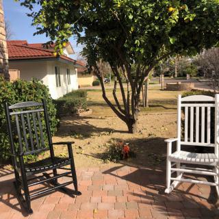 Two rocking chairs on a sunny patio with a view of a garden.