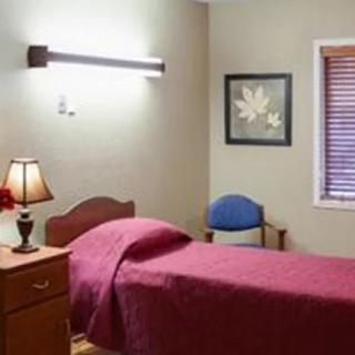 A cozy bedroom with a single bed, lamp, and wall art.