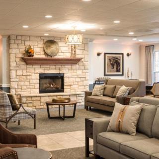 A cozy living room with modern decor featuring a stone fireplace, comfortable seating, and tasteful artwork.