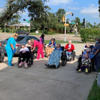 A group of seniors enjoying time outside with caregivers, creating a vibrant community atmosphere.