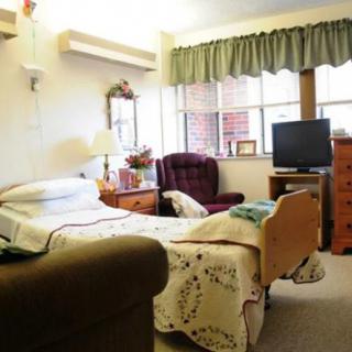 A cozy room with a hospital bed, television, and comfortable seating.