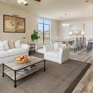 A bright and spacious living room featuring modern decor, comfortable seating, and a dining area in the background.