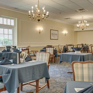 Elegantly set dining room with chandeliers and neatly arranged tables.