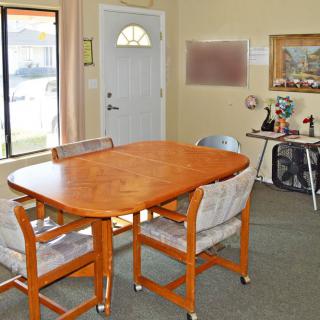 A cozy dining area featuring a wooden table with chairs, a window, and decorative artwork on the walls.
