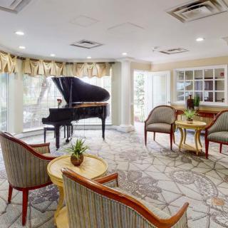 A cozy living room with a grand piano, seating area, and large windows.