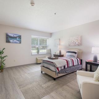 A modern and stylish bedroom with a single bed, natural lighting, and decorative artwork.