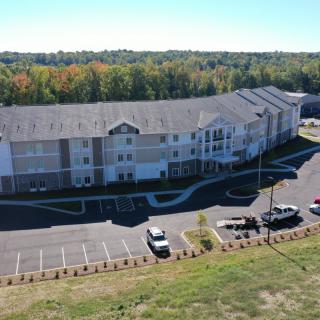 Aerial view of a residential building with a parking lot and surrounding greenery.