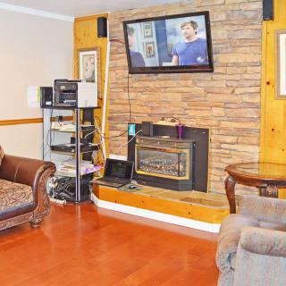 A cozy living room featuring a television mounted above a brick fireplace, with comfortable seating and wooden accents.
