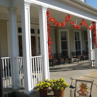 A porch decorated with autumn leaves, potted flowers, and seating area.