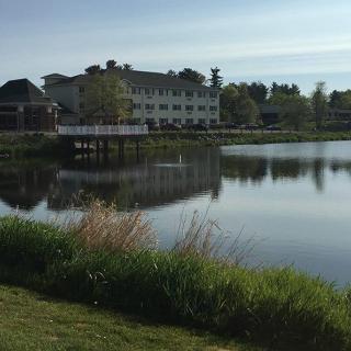 A serene view of a building by the lake with its reflection in the water.