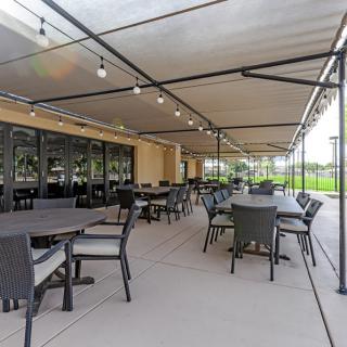 A spacious outdoor patio with tables and chairs under a covered area, adorned with string lights.