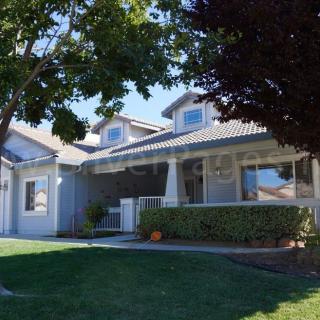 A suburban house with a well-maintained yard and trees under a sunny sky.