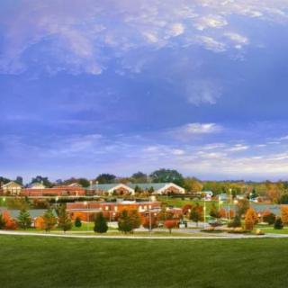 A suburban landscape in autumn with colorful trees and buildings under a wide sky.