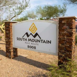 A sign for South Mountain real estate, supported by brick pillars, set in a desert landscape.