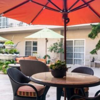 A cozy outdoor patio with a table, chairs, and umbrellas surrounded by plants.