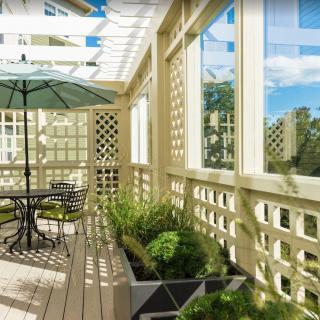 A sunny patio with a table, umbrella, and potted plants.