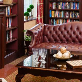 A cozy library living room with a leather sofa, bookshelf, and elegantly arranged coffee table.