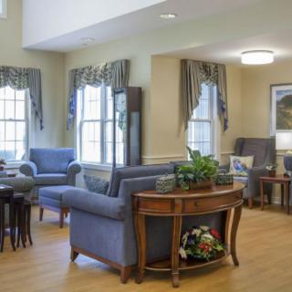 A cozy living room with classic furniture and large windows adorned with drapes.