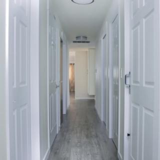 A bright hallway with multiple doors and white walls.