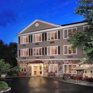 A well-lit hotel exterior at night with surrounding trees.