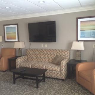 A cozy living room setup featuring a patterned sofa, armchairs, and a television mounted on the wall.