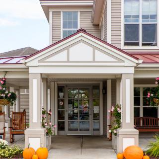 An inviting porch with pumpkins and decorations at the entrance of a building.