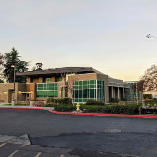 A modern commercial building featuring large glass windows and landscaped surroundings.