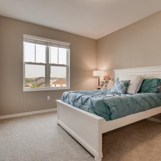 A cozy bedroom with a comfortable bed, stylish lamp, and a window overlooking the outdoors.