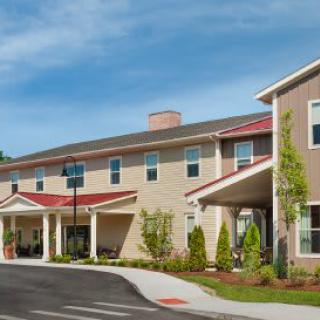 A modern residential building with a landscaped entrance under a clear blue sky.