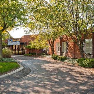 A serene view of a brick building surrounded by trees and a winding path.