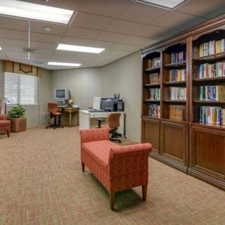 A cozy library room with bookshelves, a reading area, and a computer desk.