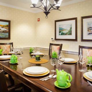 A dining room with a neatly set table and decorative green teapots.