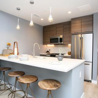A modern kitchen with a sleek island, bar stools, and stainless steel appliances.