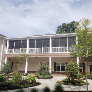A charming residential building featuring a spacious balcony, surrounded by greenery.