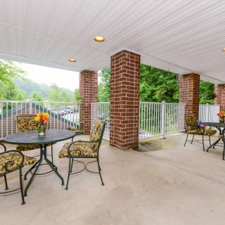 A spacious patio with tables and chairs, featuring brick columns and a scenic outdoor view.