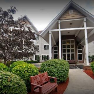 A charming building entrance with manicured landscaping and a wooden bench.