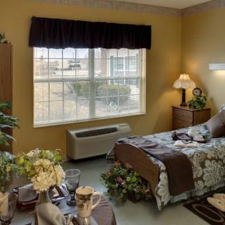 A cozy bedroom with a large window, bed, and bedside table lamp.