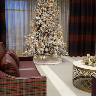 A cozy living room decorated for the holidays, featuring a beautifully adorned Christmas tree and stylish furniture.