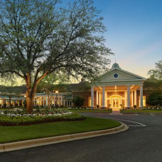 A beautifully lit hotel entrance surrounded by lush landscaping during the evening.